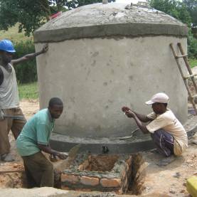 Men in rural part of Uganda constructing a rainwater harvesting tank